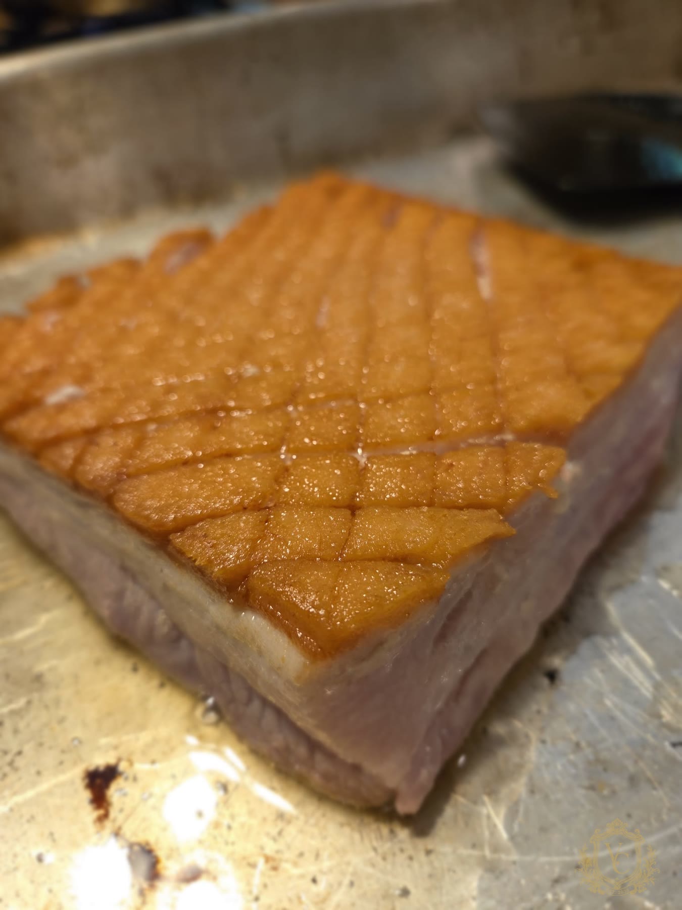 Pork belly in a pan with the fat side cooked and scored.