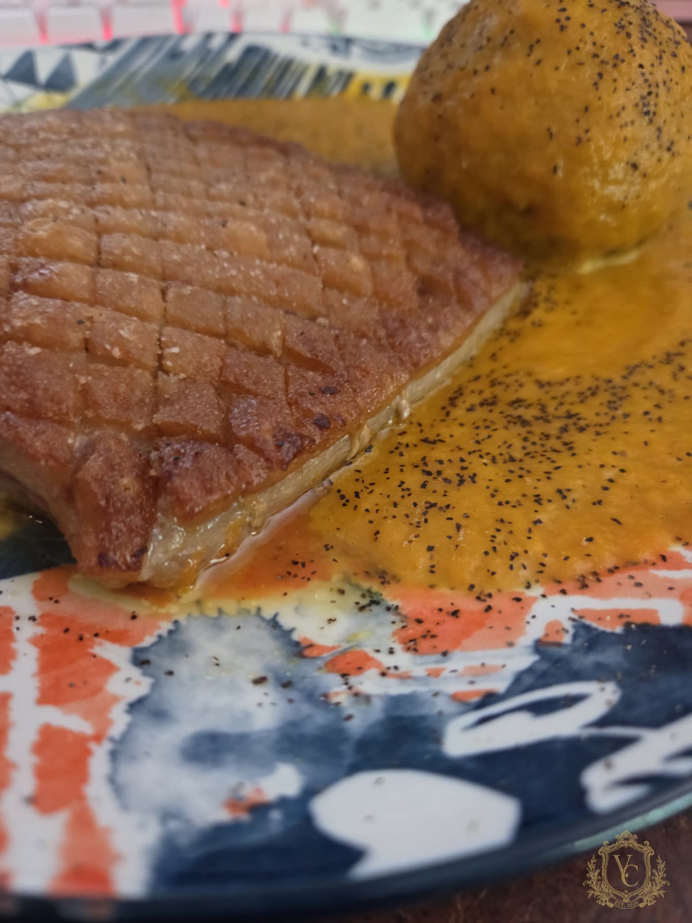 Cooked pork belly with Yukon gold potato and carrot onion beer sauce on a plate.