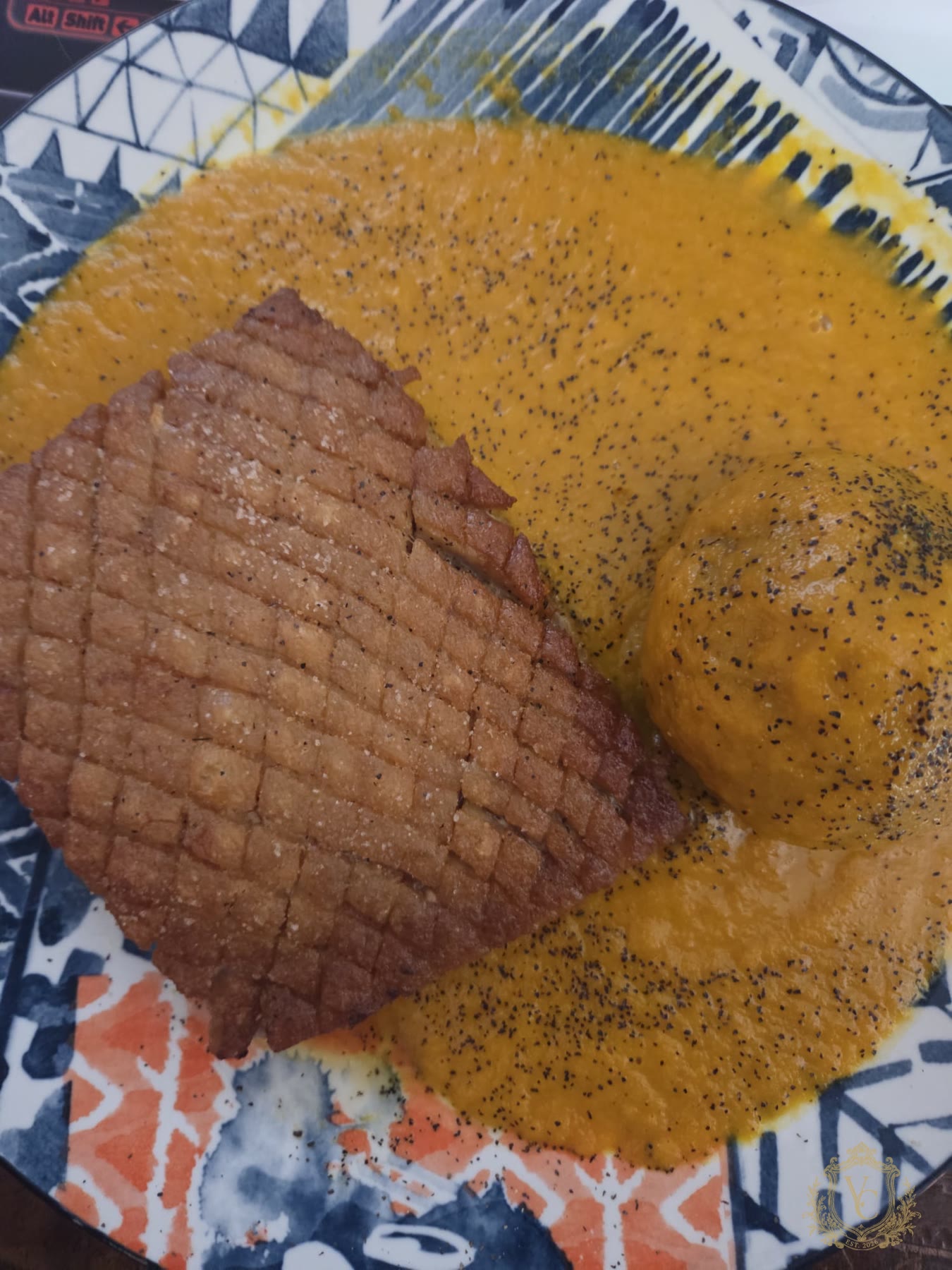 Overhead view of cooked pork belly in carrot onion beer sauce with Yukon gold potato.